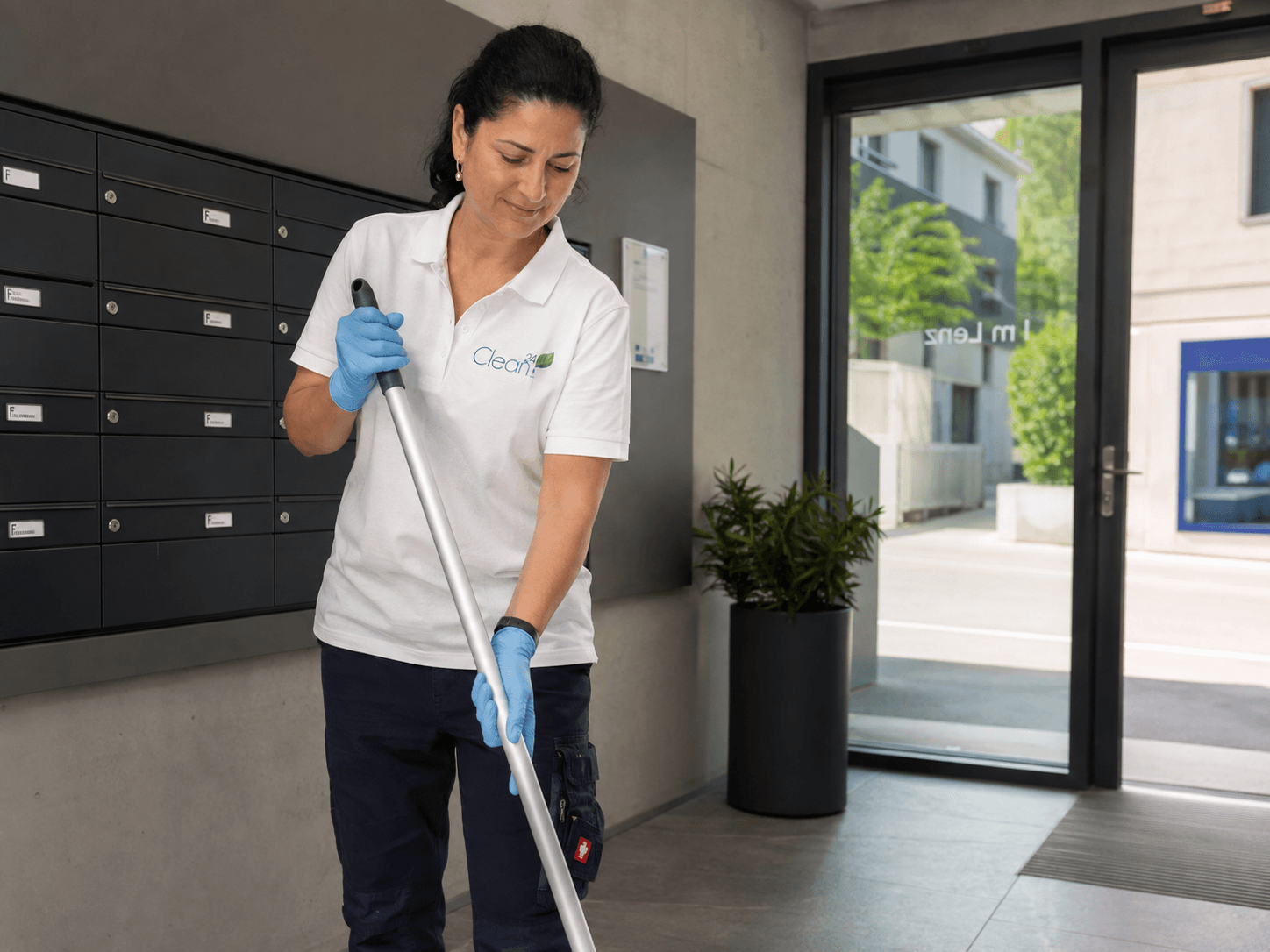 Clean24 Mitarbeiterin bei der Reinigung eines Liegenschaftseingangs.